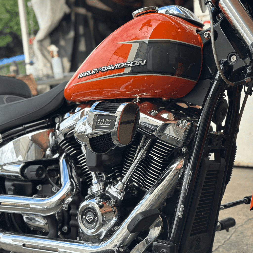 Harley-Davidson motorcycle engine with orange fuel tank and chrome details, showcasing classic bike craftsmanship.